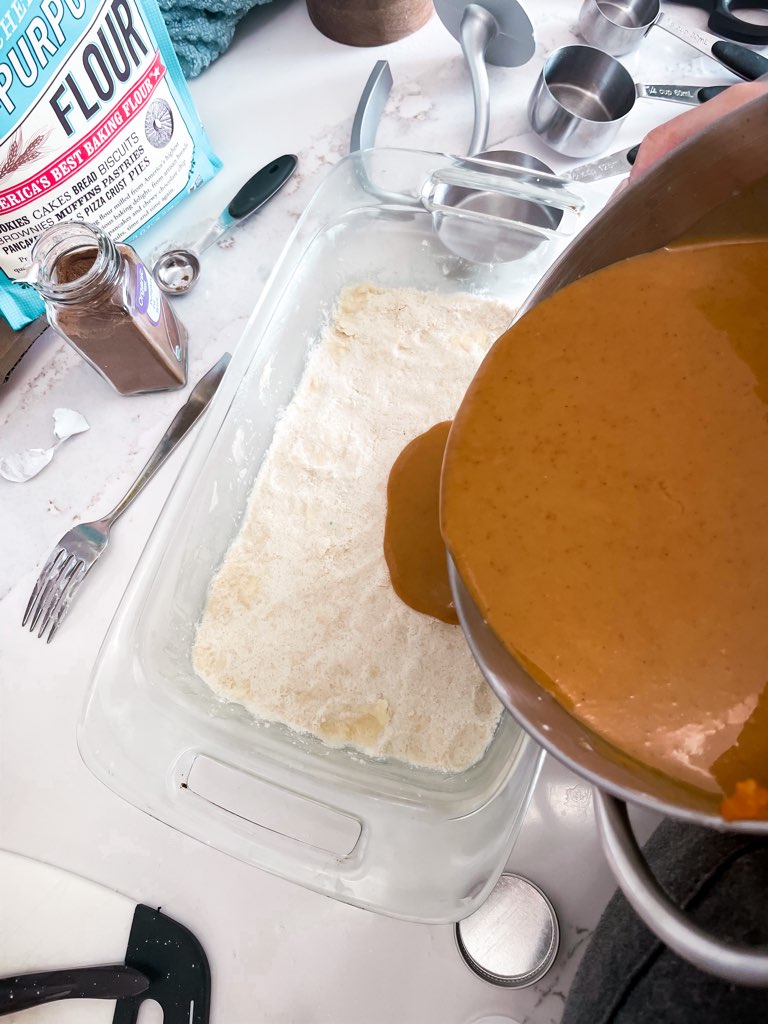 Women pouring the pumpkin pie filling onto the pressed down pie crust